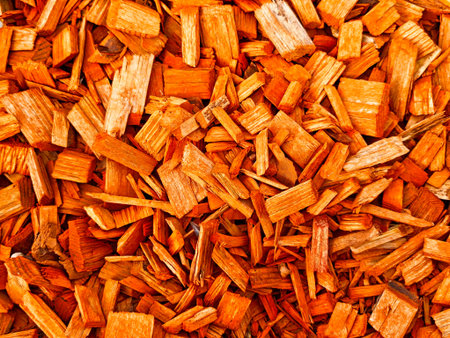 Colorful wooden chips in shades of red form a rich texture, perfect for crafting, landscaping, or decorative applications.の写真素材