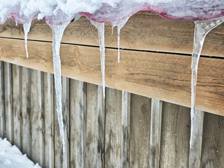 Icicles form under a roof and can fall, creating danger for anyone walking close beneath them in winter conditions.の写真素材