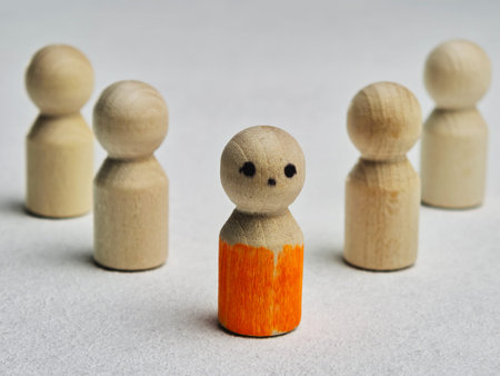 Wooden peg figures represent ideas of leadership and teamwork. One figure with an orange color...