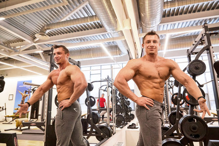 Kirov, Russia - March 15, 2021: Two bodybuilders show their muscles in the gym while others train in...