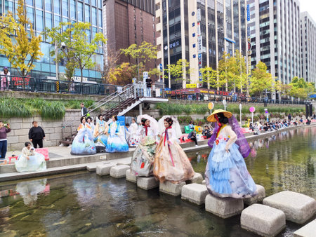 Seoul, South Korea - November 01, 2024: Groups of tourists stroll along Cheonggyecheon Stream in Seoul, South Korea. They wear bright traditional costumes while enjoying the lively urban atmosphere and local culture.のeditorial素材