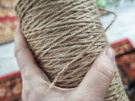 A person holds a spool of twine with one hand in a bright indoor space. This scene shows someone...