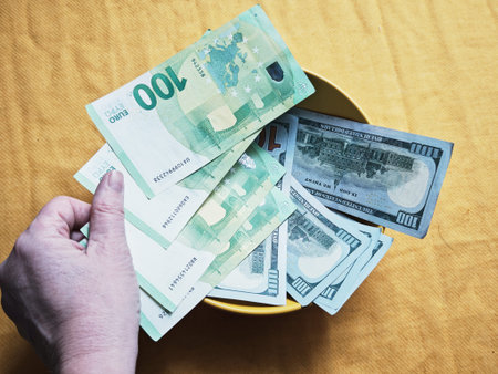 Kirov, Russia - February 20, 2026: A person is grabbing different currency notes, including Euro and...