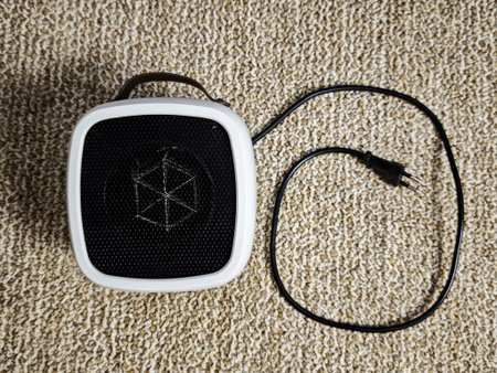 Portable electric heater is placed on carpet, ready for use to provide warmth during the cold season...
