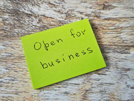 A bright green note is placed on a wooden surface indicating that the business is open. It invites...
