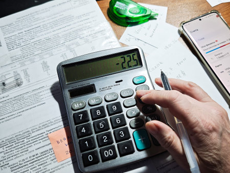 Kirov, Russia - January 19, 2026: A person calculates utility bills and household expenses using a...