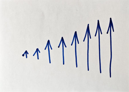 Blue lines are drawn in an upward direction on a blank surface. The lines form arrows that indicate increase and progress. This design suggests a theme of growth and development.の写真素材