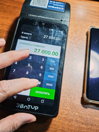 Kirov, Russia - February 27, 2026: A hand is entering a payment amount on an Evotor cash register...