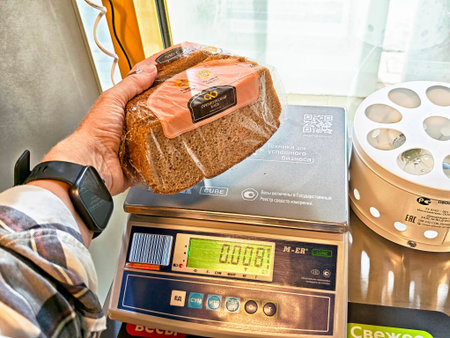 Orenburg, Russia - August 22, 2025: A person weighs a loaf of bread using a scale in the checkout...