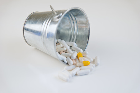 Pills for health in trash on white backgroundの写真素材