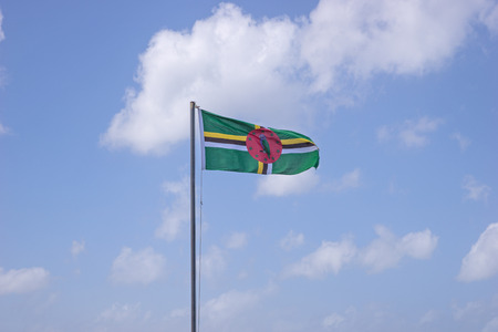 Flag of Dominica on flagpole over blue skyの写真素材