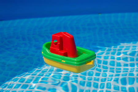 Small plastic toy boat floating in a swimming pool