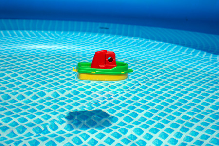 Small plastic toy boat floating in a swimming poolの写真素材