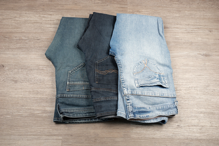 Three different blue jeans on wooden backgroundの写真素材