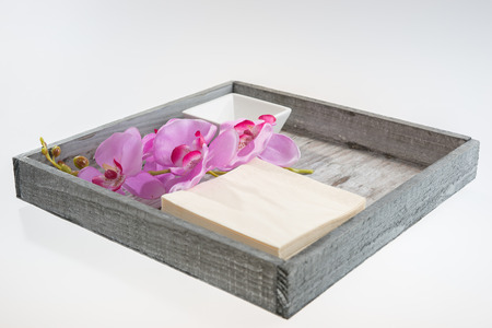 White bowl with napkin and orchid on wooden trayの写真素材