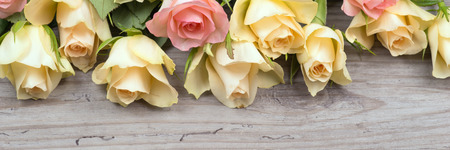 Bouquet of pink and yellow roses over wooden tableの写真素材