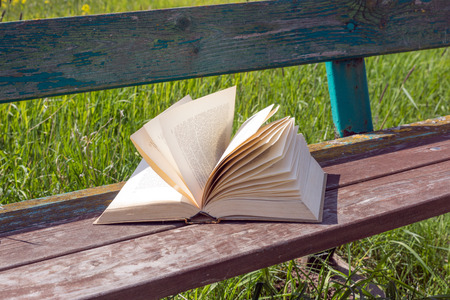 Open book on a park bench on windy dayの写真素材