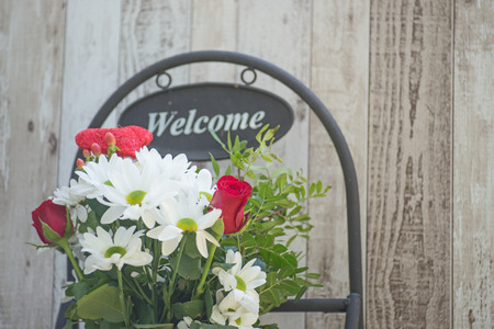 Welcome sign with spring flowers against wood backgroundの写真素材