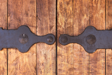 Fragment of closed old wooden gate with metal fittings