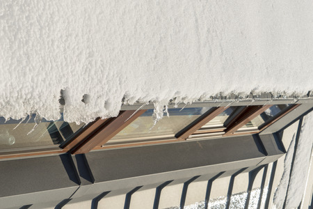 Snow hanging on the roof above the windowsの写真素材
