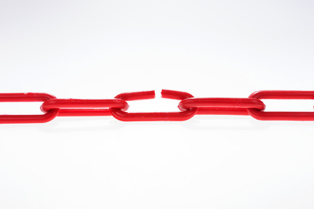 Red chain with broken element on white backgroundの写真素材