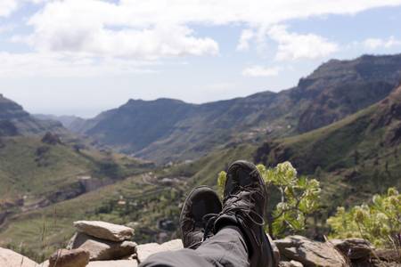Man lies on the mountain, with a view into the valley and the mountainsの写真素材