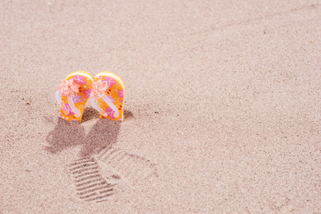 Colorful flip flops with flowers on the sandy beachの写真素材