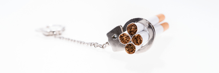 Addition concept with cigarettes and handcuffs on white backgroundの写真素材