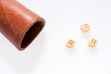 Three dice with leather cup on white background