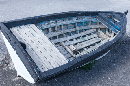 Old blue wooden boat on black sand at the beach