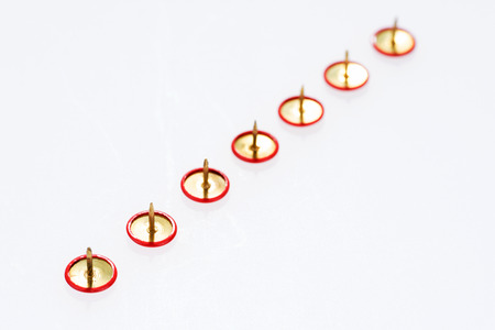 Row of red thumbtacks isolated on white background