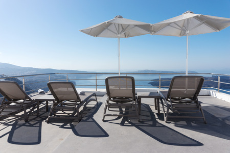 Sun loungers and parasol on the terrace overlooking the Mediterranean at Oia, Santoriniの写真素材