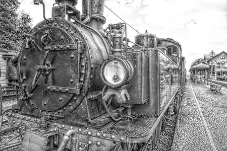 Historic steam powered train at train station in black and white