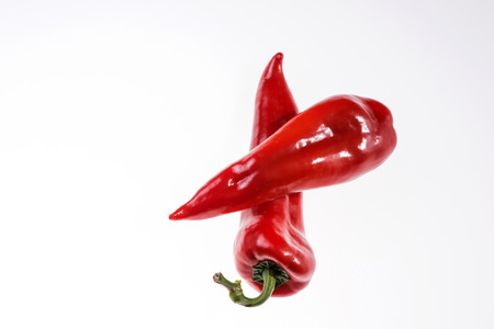 Two fresh red bell peppers isolated on a light backgroundの写真素材