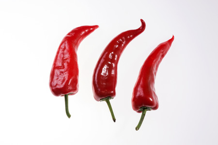 Three fresh red bell peppers isolatedの写真素材