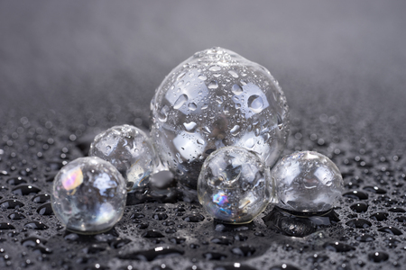 Transparent glass sphere with drops of water isolated on black backgroundの写真素材