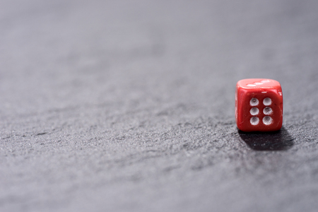 Single red dice on black background. Six side cube with white dotsの写真素材