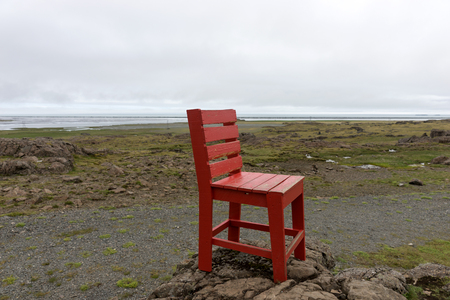 Red wooden chair on a rock. Abstract landscape in Icelandの写真素材