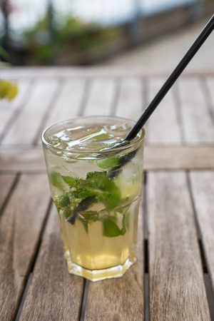 Natural lemonade with lime and mint in glass on wooden table in a outdoor restaurantの写真素材