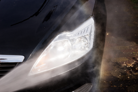 Cleaning the headlight of the car - car washing under high pressure waterの写真素材