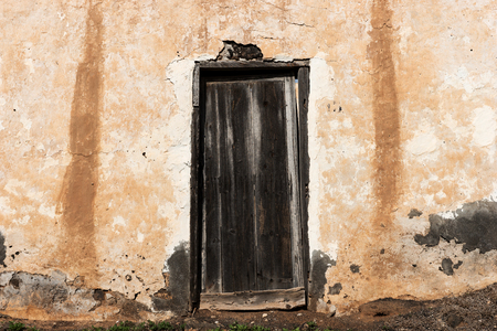 Old damaged dark wooden door in the abandoned buildingの写真素材