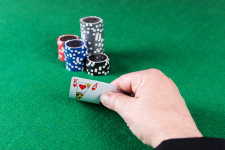 Ace of hearts and red heart in hands with poker chips in the background