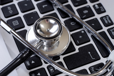 Stethoscope on modern keyboard on doctor desk. Medical science technology concept