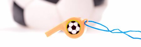 Plastic whistle with cord and soccer ball in the background. Panoramic picture