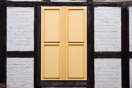 Yellow wood shutters of a medieval half-timbered house. Ancient architectureの写真素材