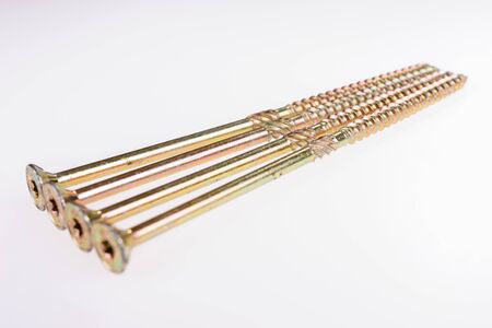 Four long metal tapping screws with heads forward. Isolated on white background