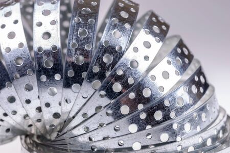 Closeup metal galvanized rolled steel band with holesの写真素材