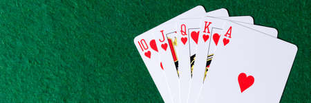 Panoramic image. Royal flush of hearts on green background. Winning hands of poker playing cards