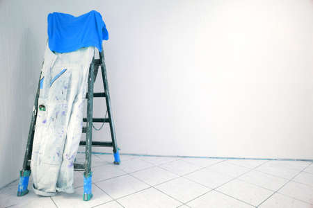 Wooden ladder with painter pants and blue T-Shirt in a room