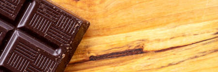 Part of the dark chocolate isolated on wooden background. Panoramic imageの写真素材